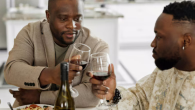Two men sharing a toast with red wine during a cozy dinner at home.